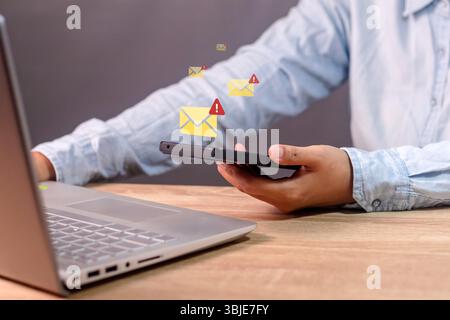 A business woman receives a malicious message on her smartphone. Email or message notification with warning symbol on smartphone. Stock Photo