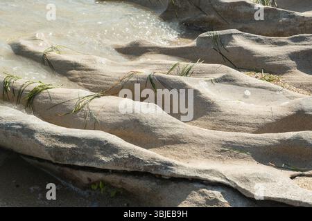 Beautiful eroded stone on calm sea waters on sunny summer day on the beach closeup Stock Photo