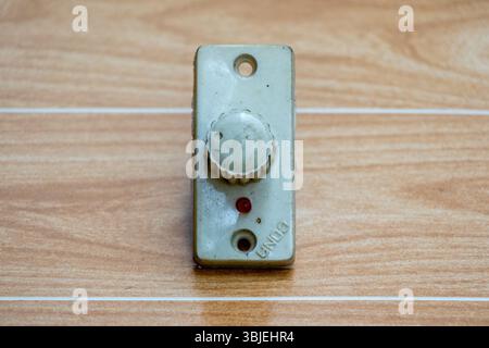 Vintage fan speed regulator with red indicator light, close-up on wooden texture. Stock Photo