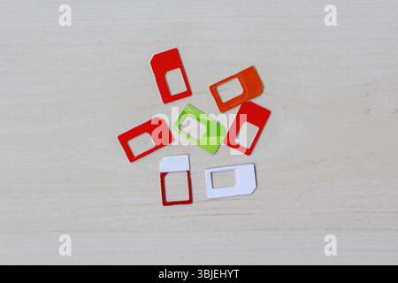 Assortment of SIM cards in various sizes scattered on a wooden surface, top view. Mobile technology, telecommunications, global connectivity, subscrib Stock Photo