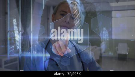 Manipulating doctor in scrubs adjusting holographic interface in hospital hallway, with stethoscope Stock Photo