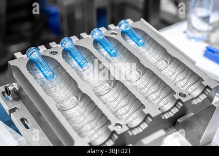 Mould of PET plastic bottles drinking water container on bottle blowing machine background Stock Photo