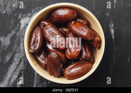 Dried dates in bowl. Brown sweet fruit. Organic healthy snack. Natural energy food. Rustic vegan ingredient. Marble texture background. Closeup macro. Stock Photo