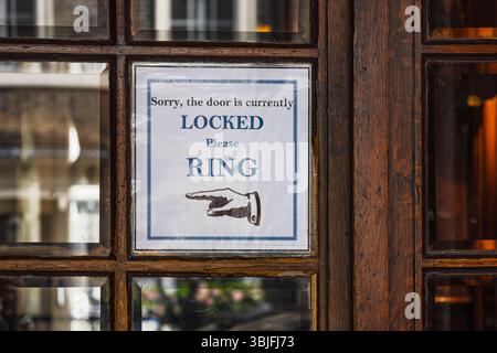 Locked Wooden Shop Door with Please Ring Paper Sign and Arrow Direction Notice Stock Photo