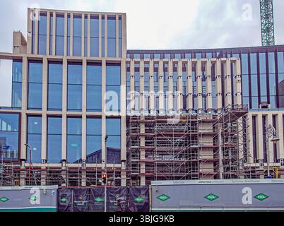 Modern office development under construction on Harcourt Street, Dublin, Ireland, with glass façade, scaffolding, and John Paul Construction signage. Stock Photo
