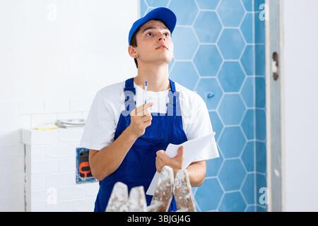 Young builder making checklist while planning indoor building overhaul Stock Photo