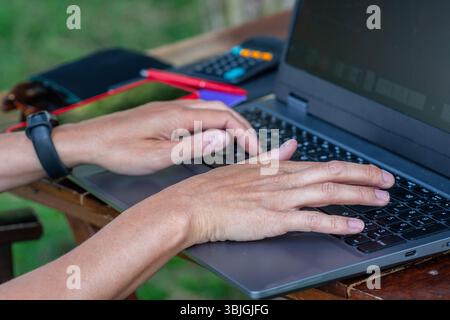 Female freelancer working remotely on laptop outdoors Stock Photo