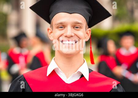 Handsome guy student posing in graduation costume Stock Photo