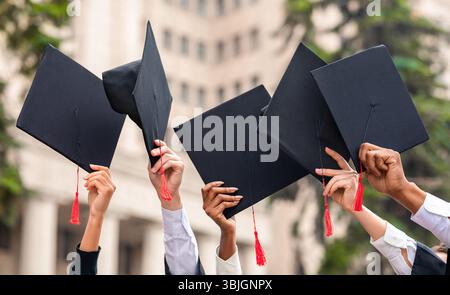 Cropped of students raising up hands with caps Stock Photo
