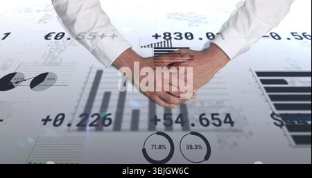 Hovering businessman clasping hands displaying bar charts, pie gauges and Euro data in office Stock Photo