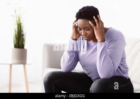 Black woman touching her head feeling stress Stock Photo