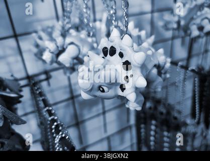 Objects keychains in form of models of toys colorful dinosaur printed on 3D printer from multi-colored molten plastic hanging on chain. Concept 3D Printing. 3D Printing additive technology. Blue color Stock Photo