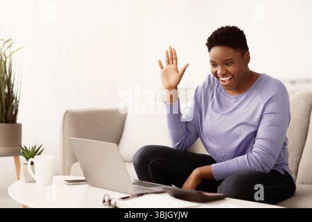 Black woman having videocall using laptop waving hand Stock Photo