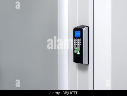 Digital screen with finger scanner and passcode panel, modern door access control on white wall at the entrance door with copy space. Fingerprint scan Stock Photo