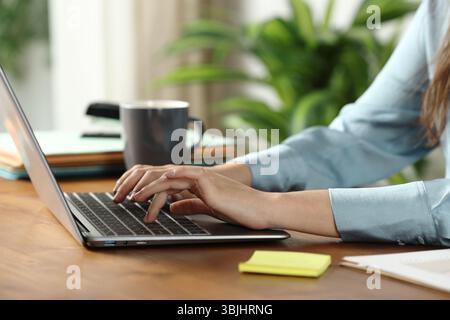 Close up of a woman hands working online typing on laptop on a wooden table at home or office Stock Photo