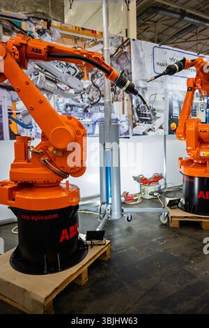 Ukraine, Kyiv - May, 27, 2025:Orange Industrial Robotic Arms on Display at Trade Show Emphasizing Innovation and Technological Advancement in Automati Stock Photo