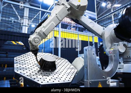 Robotic arm performs automated work on a metal part in a modern industrial factory. Manufacturing automation and technology concept Stock Photo