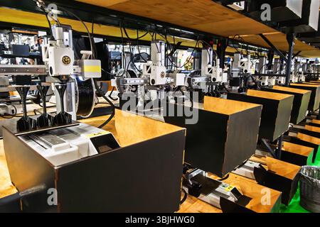 Row of 3D printers in a workshop, actively printing parts. Illustrates modern manufacturing, technology, and industrial automation. Stock Photo