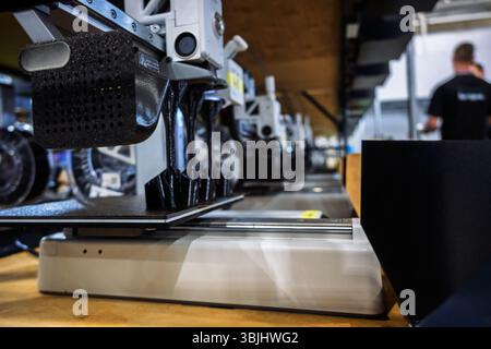 3D printer in action, fabricating parts on a build plate in a modern manufacturing facility. Focus on innovation and industrial technology Stock Photo