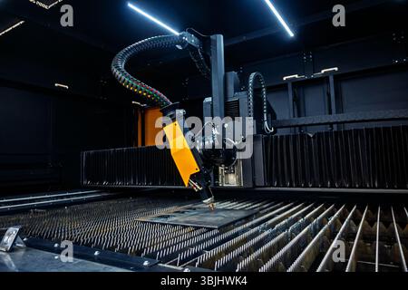 Automated laser cutting machine head processing metal plate in a dark industrial workshop. Precision manufacturing technology Stock Photo