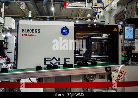 Ukraine, Kyiv - May, 27, 2025:Industrial injection molding machine on a production line with conveyor belt and molded plastic parts. Manufacturing aut Stock Photo