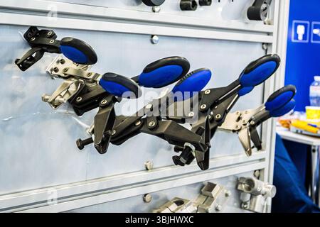 Display of industrial adjustable mechanical clamps with blue handles, on a panel at an exhibition. Shows tools, equipment, and technology for manufact Stock Photo