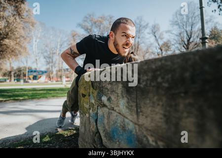 Young man performing intense parkour jump on a sunny day outdoors in an urban park setting Stock Photo