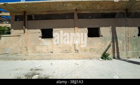 Old, weathered building with two broken windows and bullet holes in the wall. In Damascus Jobar district, Syria Stock Photo
