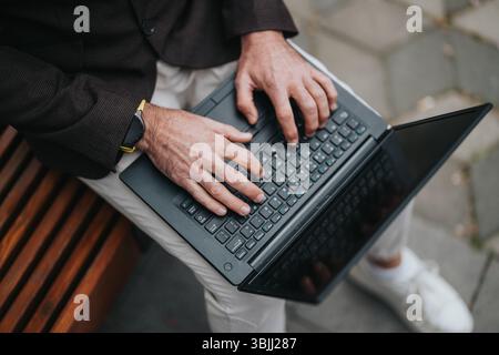 Person Typing on a Laptop While Sitting Outdoors on a Bench Stock Photo
