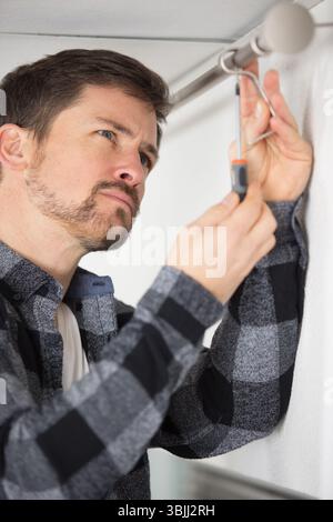 handyman installing support for curtain rail Stock Photo