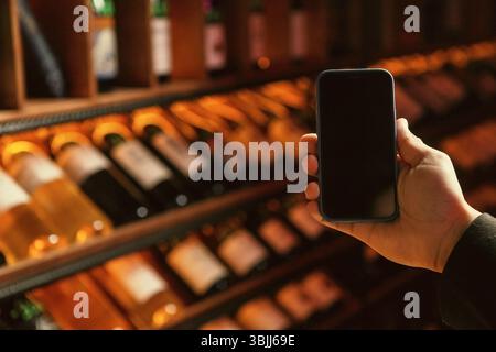 Hand Holding Smartphone in Wine Cellar Stock Photo