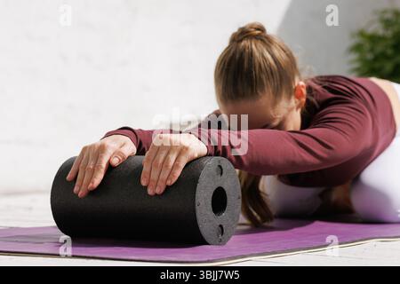 Outdoor foam roller stretching for muscle recovery, mobility, and flexibility. Modern wellness, fitness, and self-care concept. Stock Photo