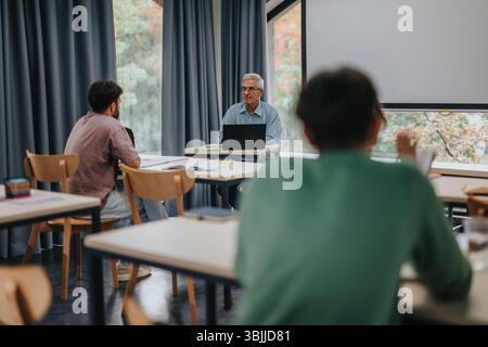 Students engaging with experienced professor in modern classroom setting Stock Photo