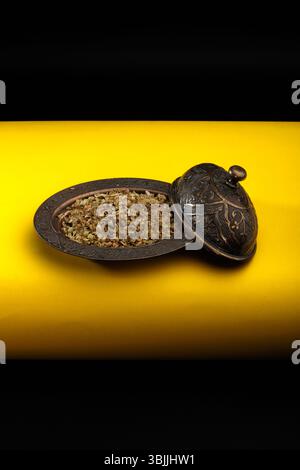 Dried thyme in a bowl on a yellow and black background. Stock Photo
