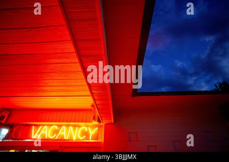 Glowing neon red Vacancy sign under ominous sky Stock Photo