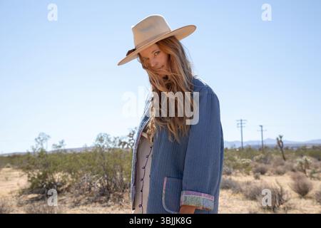 Bohemian dressed women with hat in desert  looking at camera Stock Photo