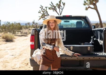 Bohemian dressed women with hat in desert and pickup truck Stock Photo