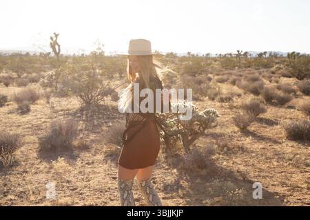 Bohemian dressed women with hat in desert dancing Stock Photo
