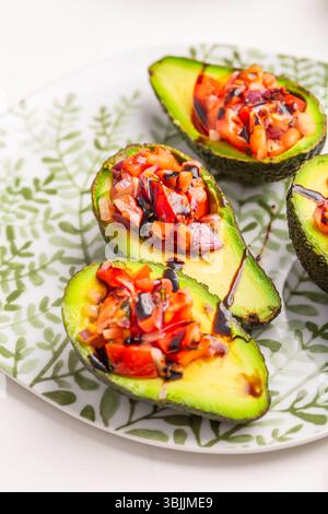 Vegan appetizers, avocados filled with bruschetta and balsamico vinaigrette Stock Photo