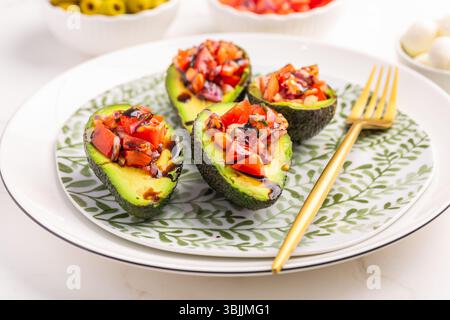 Vegan appetizers, avocados filled with bruschetta and balsamico vinaigrette Stock Photo