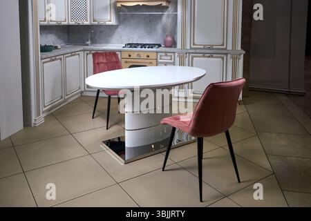 Interior of modern kitchen in classic style with golden elements in beige colors with built-in appliances gas hob electric oven stone sink and extract Stock Photo