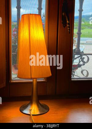 Lit up lamp by a window. Stock Photo
