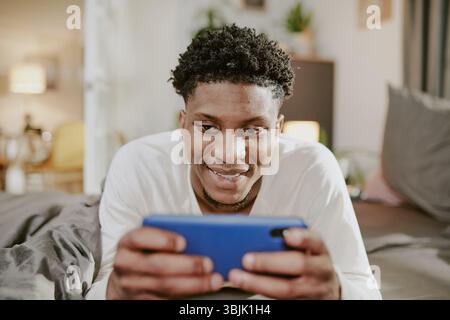 Smiling Man Using Smartphone in Cozy Indoor Setting Stock Photo