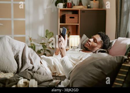 Relaxing in Bed While Using Smartphone on Cozy Evening Stock Photo