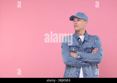 Young man wearing stylish denim baseball hat on pink background, space for text Stock Photo
