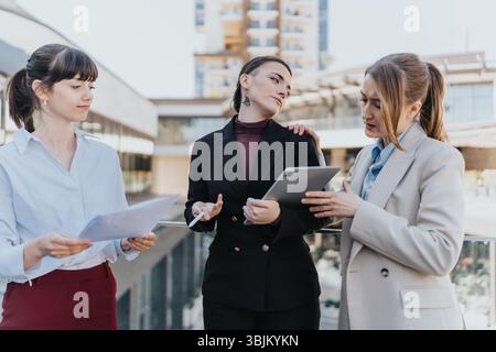 Three female business professionals collaborating outdoors in a modern urban environment Stock Photo