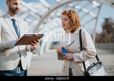 Business Professionals Discuss Project Details Outdoors in a Modern Setting Stock Photo