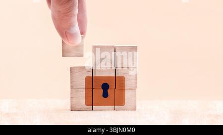 A hand carefully places a wooden piece into a jigsaw puzzle featuring a padlock design. This moment captures the essence of security and solving chall Stock Photo