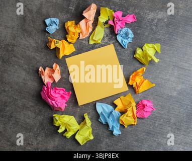 Colorful crumpled papers surround a yellow sticky note Stock Photo
