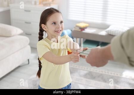 Father giving his daughter pocket money at home, closeup Stock Photo